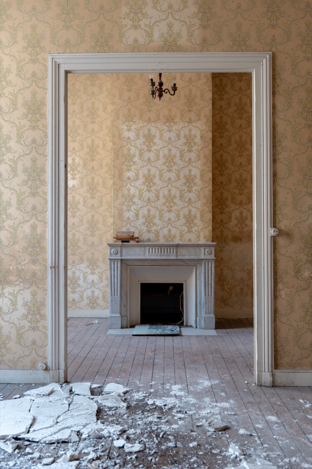 Salon d'immeuble bordelais avant travaux — papier peint d'origine et cheminée en marbre